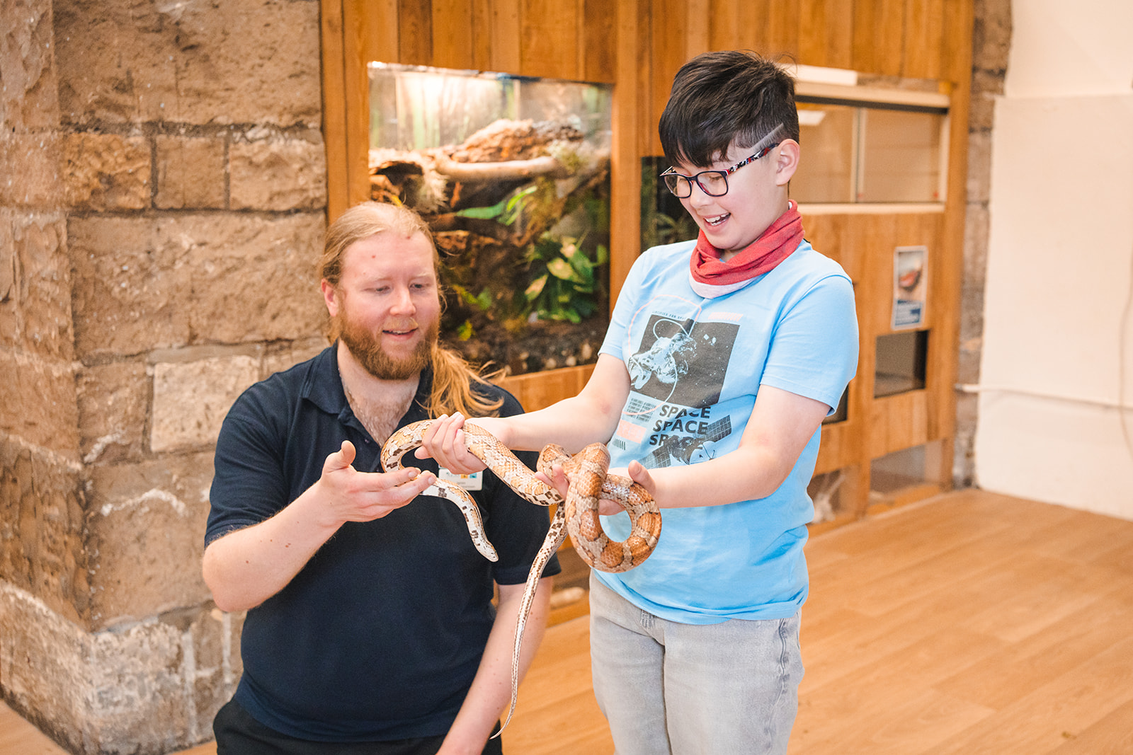 keeper with child holding corn snake and smiling IMAGE: Rachel Hein 2024