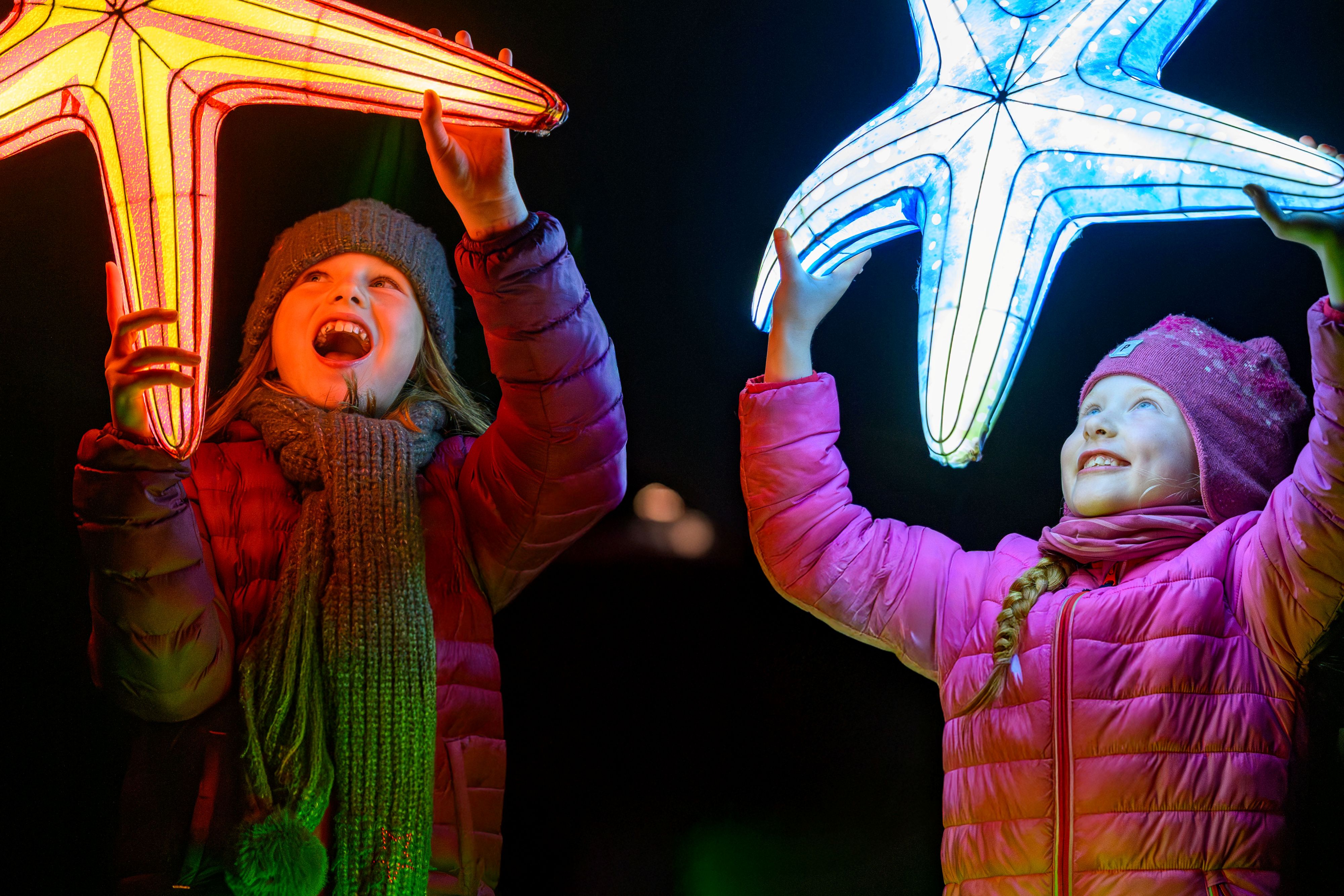 girls holding stars at giant lanterns