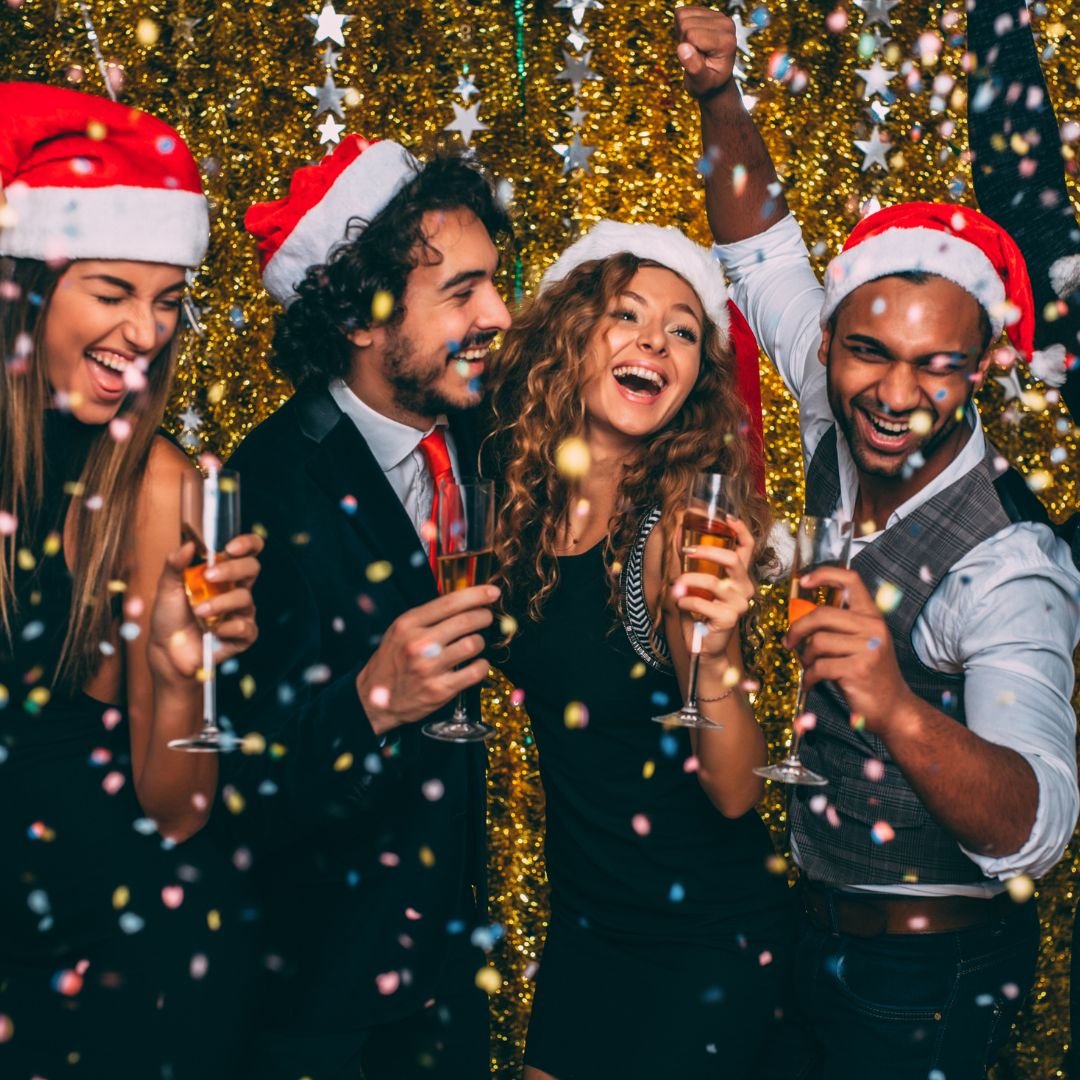 Stock image of four individuals in santa hats enjoying a festive party IMAGE: Compass, 2024