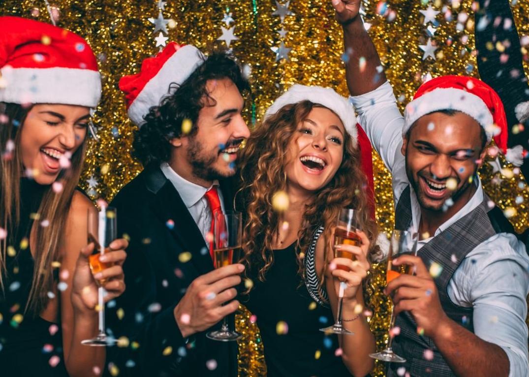 Stock image of four individuals in santa hats enjoying a festive party IMAGE: Compass, 2024