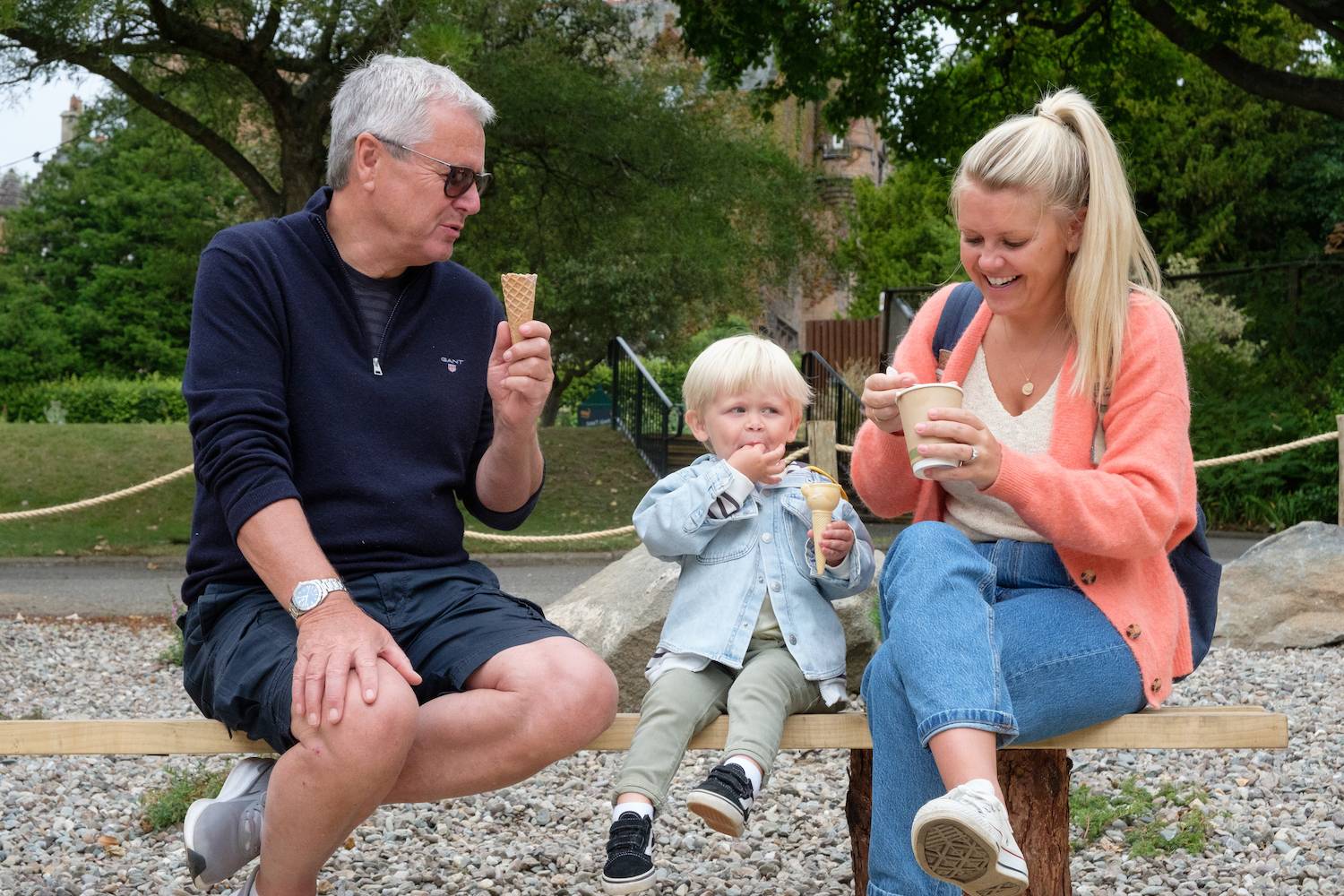 Edinburgh Zoo visitors family with young kid (boy) sitting on bench by marquee with ice cream. IMAGE: Robin Mair 2022