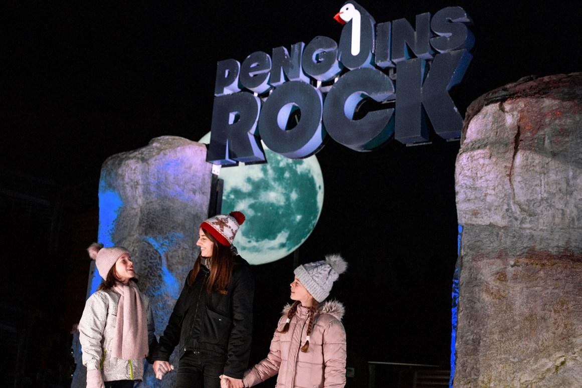 Group emerging from Penguins Rock standing under signage, lit up with moon light in background