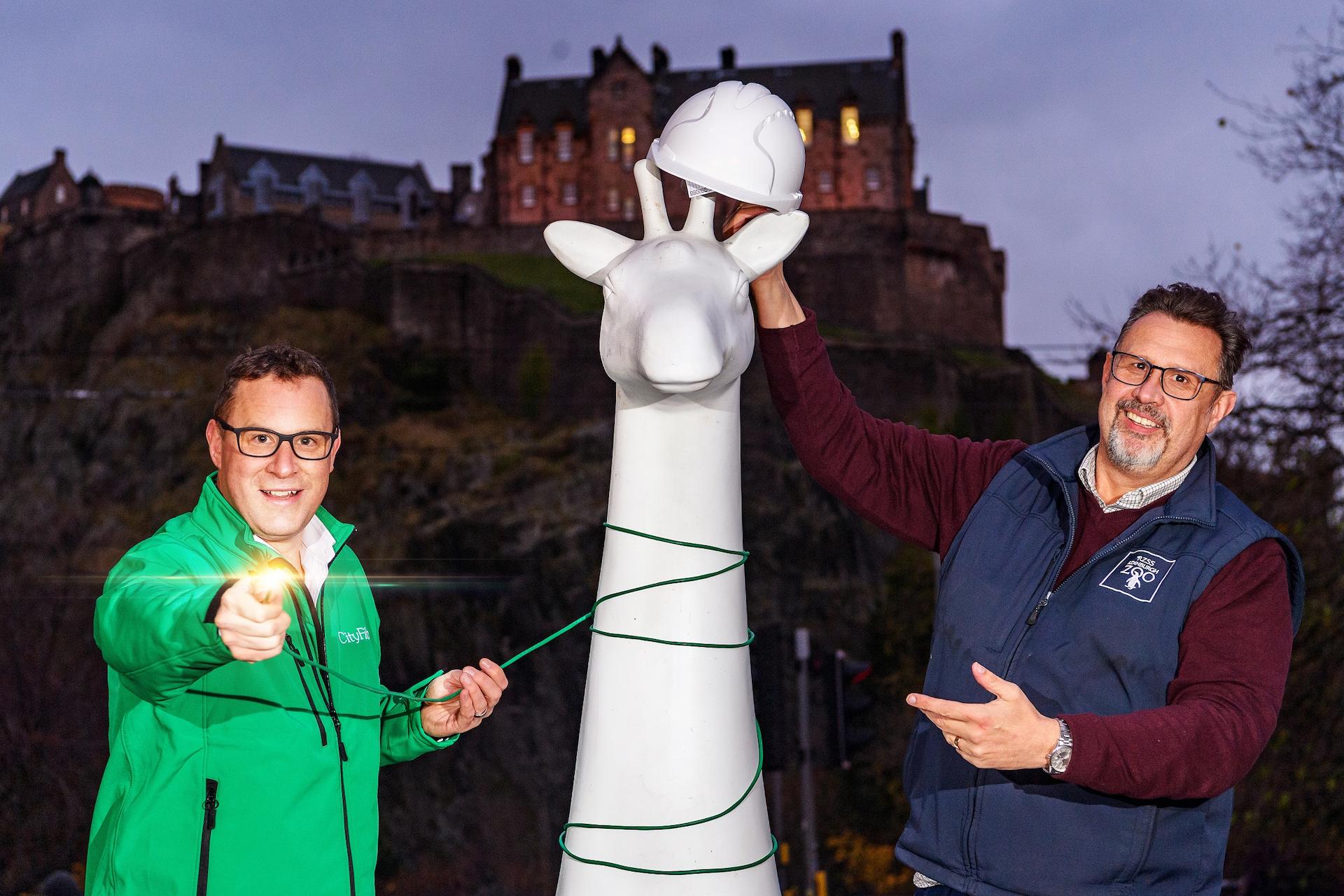 City Fibre Paul Wakefield and RZSS CEO David Field post together with blank Giraffe About Town statue, wire and hard hat in front of Edinburgh Castle

Image: 2021