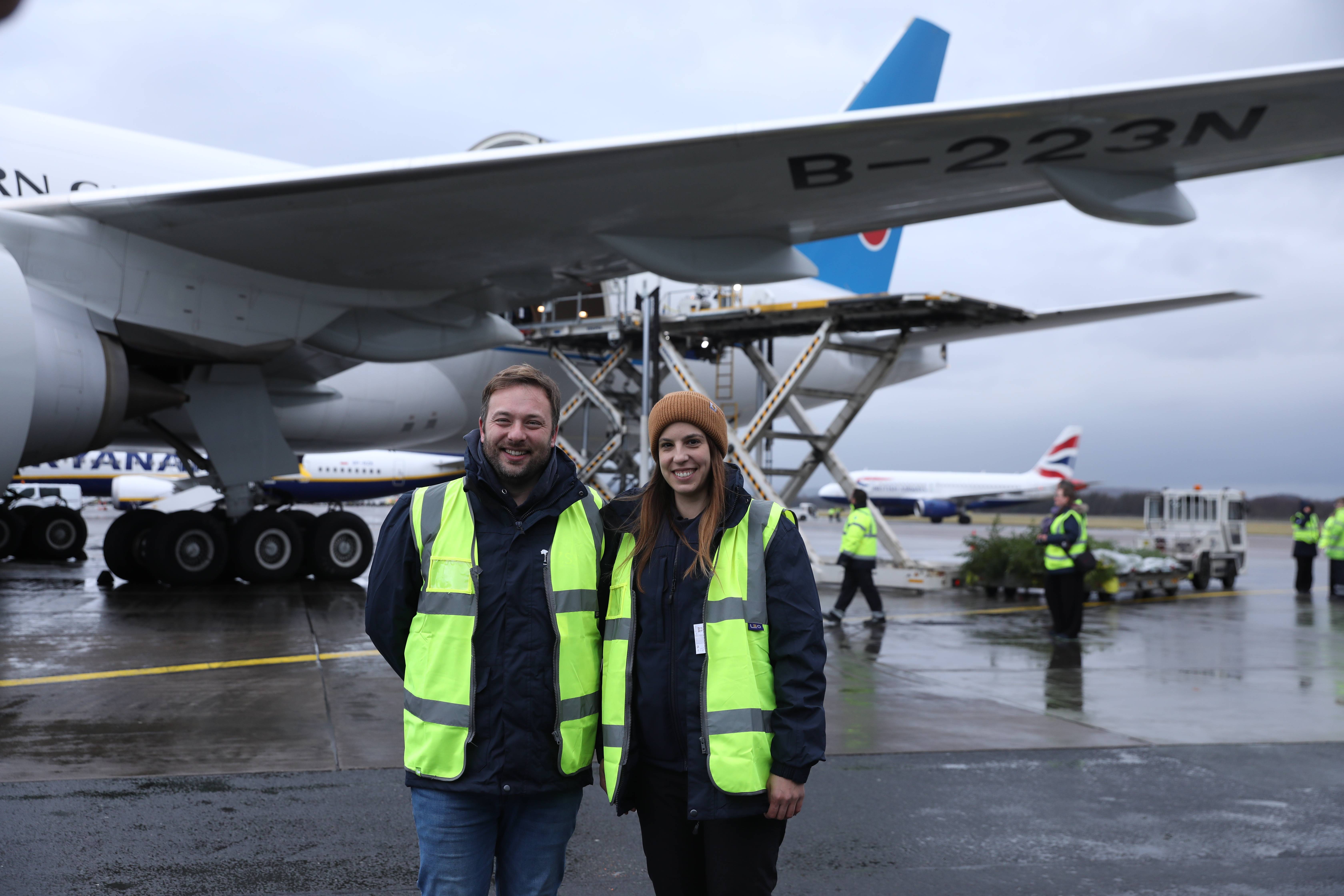Carnivore Keeper Michael Livingstone and Vet Stephanie Mota pose together smiling in high vis in front of plane taking the panda pair to China